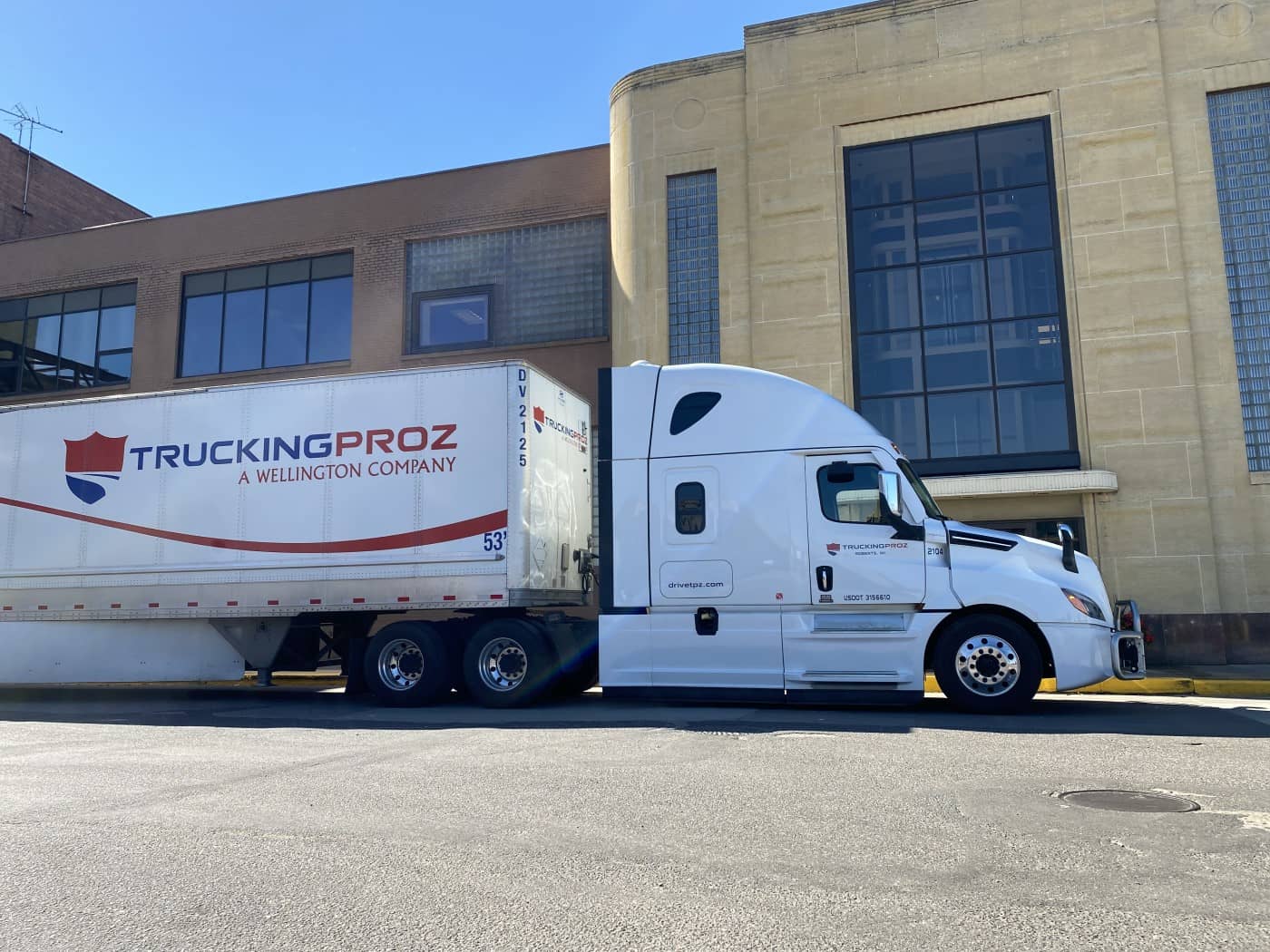 A Trucking Proz Volvo truck and trailer visiting a customer to make a delivery on sunny day.