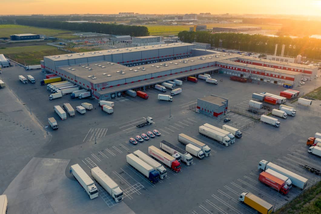 An aerial shot of a warehouse and yard with many trucks coming and going from the dock doors.