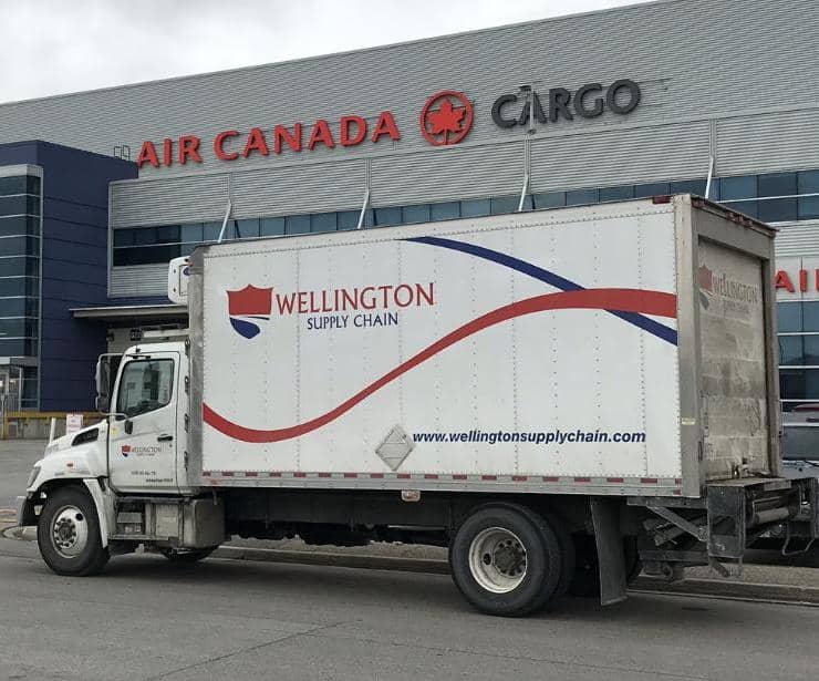 A Wellington Supply Chain straight truck parked outside of the Air Canada cargo terminal at Toronto Pearson International Airport.