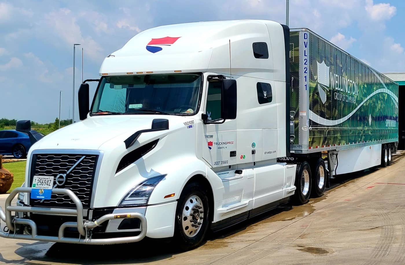 Wellington Motor Freight Volvo truck pulling a trailer wrapped in camo print.